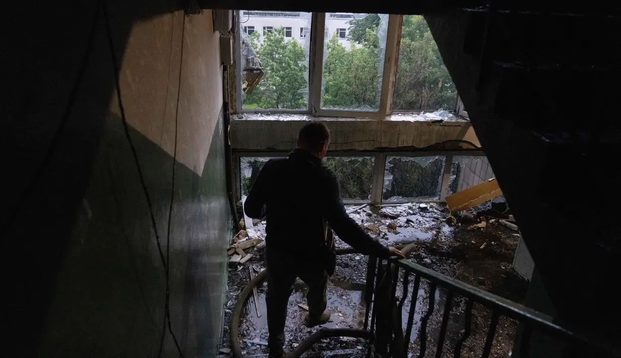 Seorang warga membawa barang-barangnya dari sebuah bangunan tempat tinggal yang rusak menyusul serangan rudal Rusia di Kyiv, Ukraina, Senin 15 Juni 2026, di tengah invasi Rusia. (OLEKSII FILIPPOV/AFP)