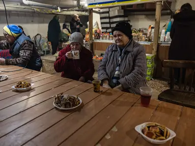 Penduduk setempat berkumpul di ruang bawah tanah di bawah pemadaman listrik di kota Bakhmut, Ukraina timur (22/12/2022). Mereka mencari perlindungan karena penembakan hebat oleh pasukan Rusia. (AFP/Sameer Al-Doumy)