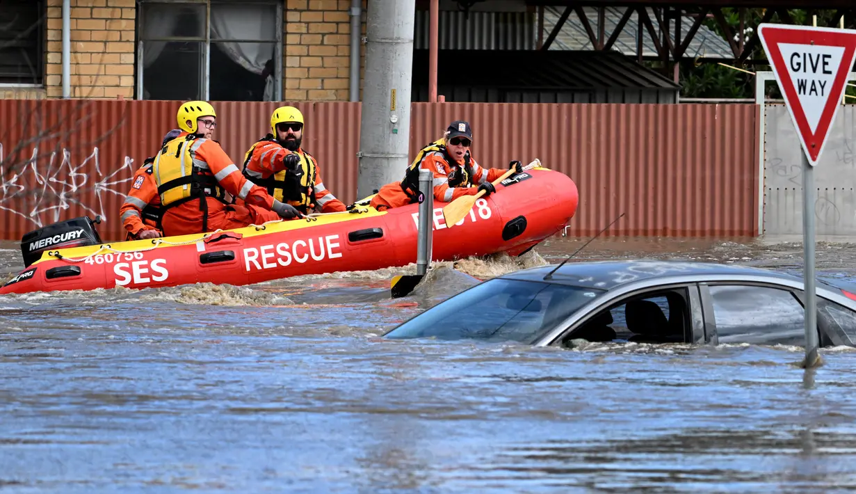 Pekerja darurat melihat mobil yang terendam banjir di pinggiran Kota Melbourne, Maribyrnong, Australia, Jumat (14/10/2022). State Emergency Service atau SES melaporkan ada satu orang hilang akibat dampak meluapnya Sungai Loddon. Namun, sejauh ini belum ada kabar korban jiwa. (William WEST/AFP)