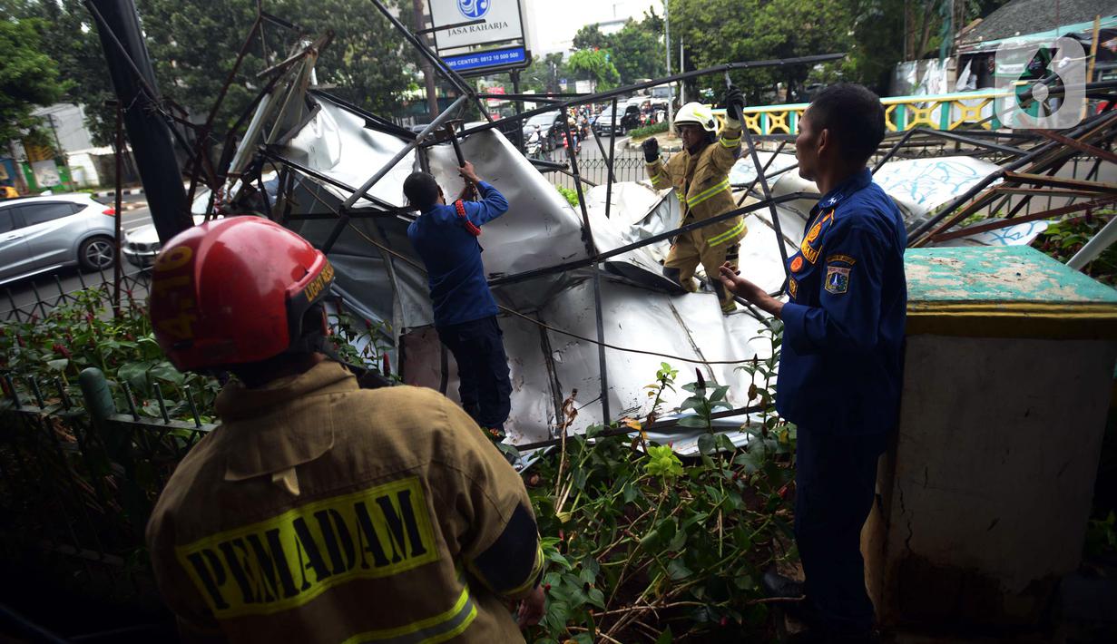 Petugas pemadam kebakaran memotong rangka reklame di Jalan Soepomo, Jakarta, Sabtu (28/5/2022). Hujan disertai angin kencang pada pagi tadi membuat papan reklame roboh sehingga membuat kemacetan arus lalu lintas di jalan tersebut. (merdeka.com/Imam Buhori)