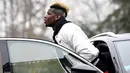 Gelandang Prancis Paul Pogba keluar dari mobil saat tiba di markas timnas sepak bola Prancis di Clairefontaine-en-Yvelines, (19/3). Pogba tampil dengan gaya rambut yang baru dengan warna emas dan hijau. (AFP Photo/Franck Fife)