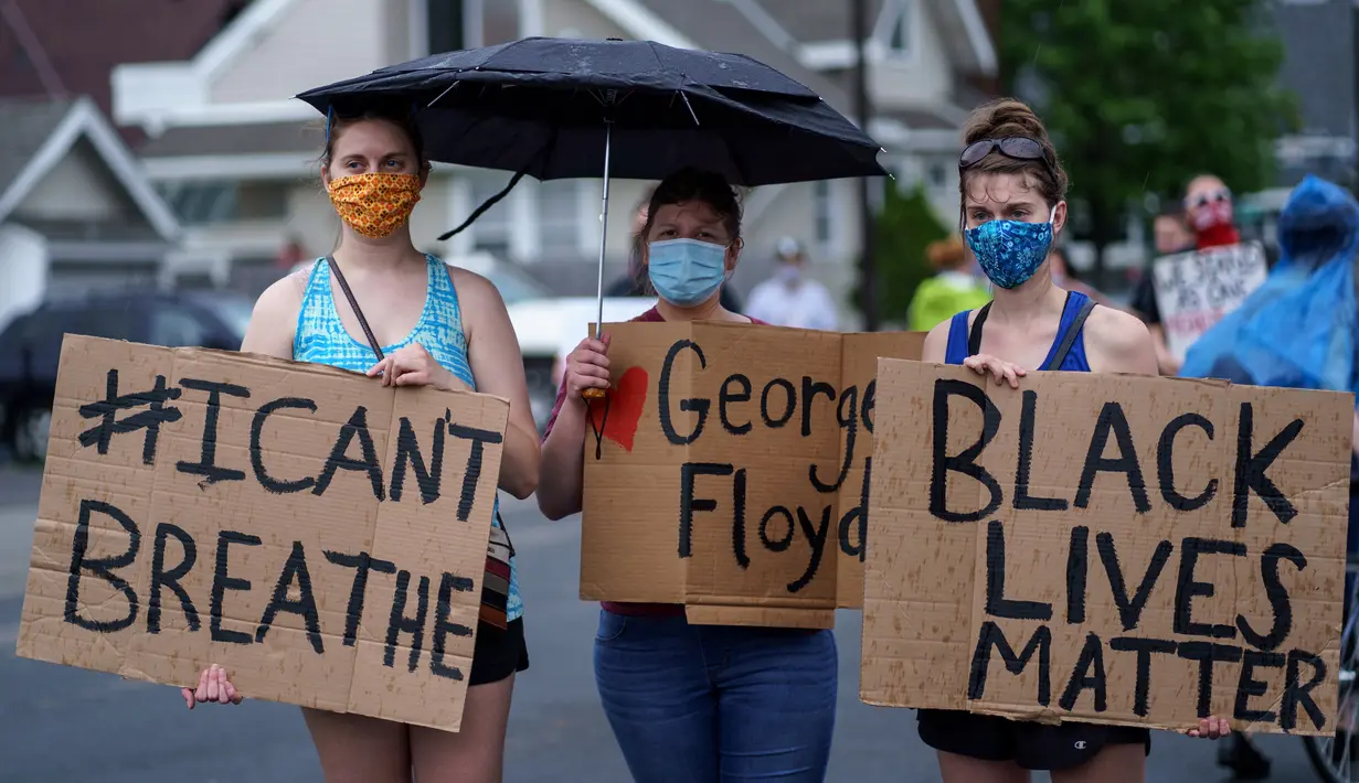 Sejumlah wanita memegang spanduk saat unjuk rasa atas kematian George Floyd oleh polisi di dekat TKP di Minneapolis, Minnesota, Amerika Serikat, Rabu (27/5/2020). Mayoritas demonstran hadir sambil membawa spanduk bertuliskan "I Can't Breathe" dan "Justice 4 Floyd". (Kerem Yucel/AFP)
