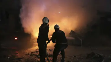 Sejumlah relawan White Helmets memadamkan api setelah pengeboman Kantor Ajnad al-Koukaz di Idlib, Suriah, Minggu, (7/1). Ajnad al-Koukaz merupakan kelompok militan yang kebanyakan dari Kaukasus dan Rusia. (Syrian Civil Defense White Helmets via AP)
