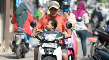 Pengendara motor tidak mengenakan masker masuk ke Pasar Bukit di Tangerang Selatan, Banten, Rabu (22/7/2020). Warga masih tidak peduli kesehatan dirinya sendiri dan orang lain, tentang bahayanya penyeberan virus corona (COVID-19) yang terus meningkat di Indonesia. (merdeka.com/Dwi Narwoko)