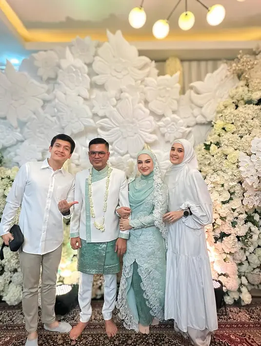 Hadiri pernikahan Irish Bella, Dhini Aminarti tampil simple denga dress panjang berlengan balon. Outfit serba putih ini dipadu dengan hijab panjang berwarna putih [@dhiniaminarti]