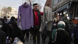 Seorang pramuniaga mengangkat pakaian perempuan untuk dijual di bazaar bersejarah tua Teheran, Iran, Minggu (26/2/2023). Inflasi pada bulan Januari lalu mencapai 53,4%. Menurut Pusat Statistik Iran, angka inflasi ini memburuk dibanding dua tahun lalu yang mencapai 41,4%. (AP Photo/Vahid Salemi)