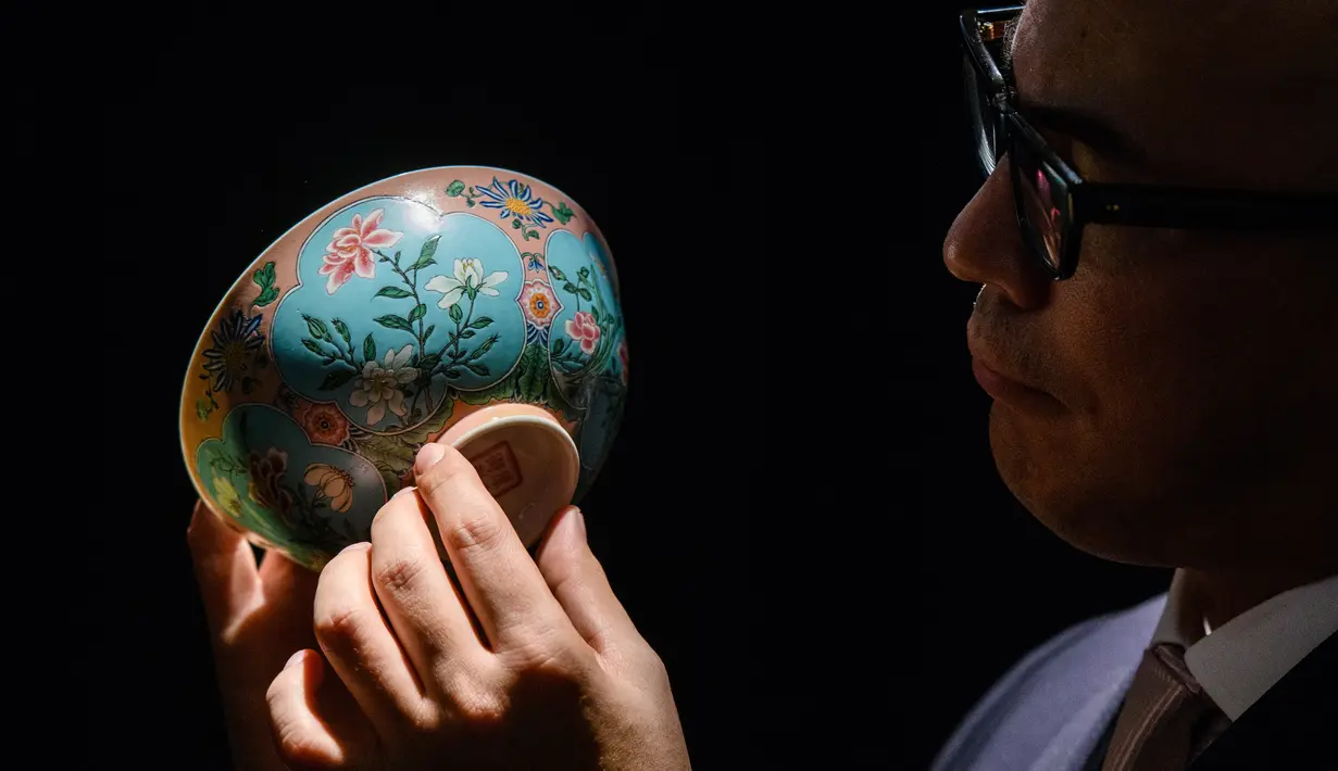 Wakil Ketua Sotheby's Asia, Nicolas Chow memegang mangkuk Dinasti Qing saat dipamerkan di Rumah Lelang Sotheby's di Hong Kong, Kamis (2/3). Diperkirakan, mangkuk ini akan terjual seharga USD 25,6 juta atau sekitar Rp 348 miliar. (ANTHONY WALLACE/AFP)