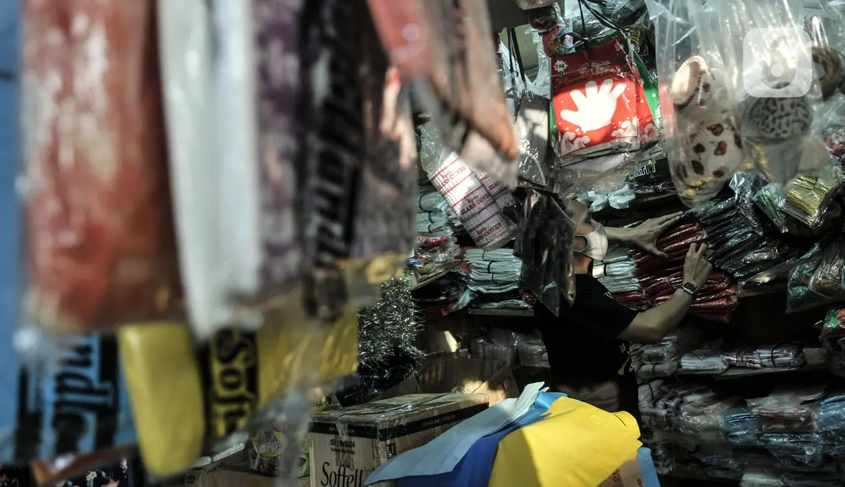 Abdullah (37) merapikan kantong plastik sekali pakai yang dijualnya di Pasar Tebet Barat, Jakarta, Selasa (30/6/2020). Jelang pemberlakuan larangan penggunaan plastik sekali pakai, Abdullah mengaku penjualan kantong kresek di tokonya menurun hingga 30 persen. (merdeka.com/Iqbal S Nugroho)