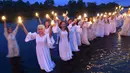 Gadis-gadis Belarusia memegang lilin saat berdiri di Sungai Berezina pada Hari Ivan Kupala di Desa Parichi, sekitar 200 km (125 mil) selatan Parichi, Belarusia, 6 Juli 2022. Ivan Kupala atau Hari St. John atau Hari Pertengahan Musim Panas adalah karnaval tradisional yang berpusat di sekitar api unggun dengan banyak makanan dan tarian. (AP Photo/Viktor Drachev)