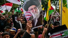 Seorang anak laki-laki memegang plakat bergambar pemimpin tertinggi Iran, Ayatollah Ali Khamenei yang gugur dalam serangan Amerika Serikat dan Israel pada akhir Februari lalu, selama berunjuk rasa memperingati Hari Al-Quds, di Surabaya, Jawa Timur, Jumat (13/3/2026). Ratusan orang turun ke jalan menggelar aksi unjuk rasa memperingati Hari Al-Quds Internasional. (Juni KRISWANTO/AFP)