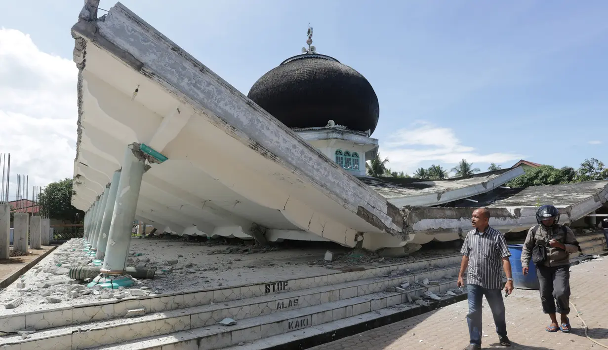 Warga melintas di depan masjid yang roboh usai gempa di Meuredu, Pidie Jaya, Aceh, Rabu (7/11). Selain meruntuhkan bangunan, gempa bumi berkuatan 6,4 SR ini telah menelan banyak korban jiwa. (Antara Foto / Irwansyah Putra / via REUTERS)