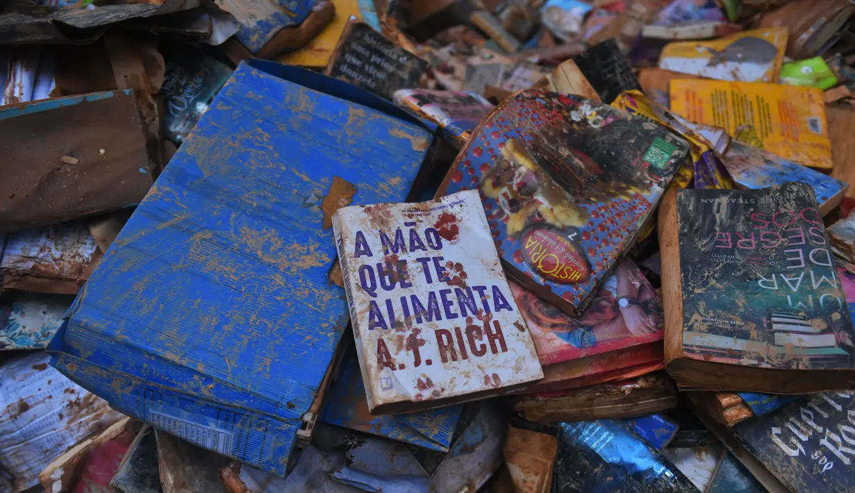 Buku-buku rusak terlihat di jalan setelah hujan lebat membanjiri toko buku di Petropolis, Brasil, 19 Februari 2022. Sebanyak 136 jenazah telah diidentifikasi hingga kini, menurut pejabat pertahanan sipil, di kota wisata yang biasanya indah, sekitar 60 km utara Rio de Janeiro. (MAURO PIMENTEL/AFP)