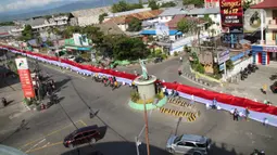 Pelajar SMA membentangkan bendera Merah Putih sepanjang 2,3 kilometer di Jalan Panjaitan dan Jalan Nani Wartabone, Gorontalo, Kamis (23/1/2020). Bendera dibentangan di tempat deklarasi kemerdekaan Gorontalo pada 23 Januari 1942. (Liputan6.com/Arfandi Ibrahim)