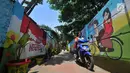 Seorang remaja mengendarai sepeda motor melintas di 'Gang Mural', Kelurahan Rorotan, Jakarta, Kamis (29/3). Setiap tembok gang sepanjang 100 meter tersebut dihiasi dengan berbagai mural atau gambar kartun inspiratif. (Merdeka.com/Iqbal S Nugroho)