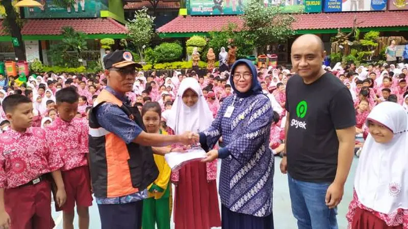 Kepala BPBD DKI Jakarta Subejo secara simbolis memberikan bantuan seragam sekolah dari Gojek kepada Kepala SDN Kapuk Muara 03 Melfa Christine, didampingi SVP Public Policy and Government Relations Gojek Panji Ruky di Penjaringan, Jakarta Utara. Dok: Gojek