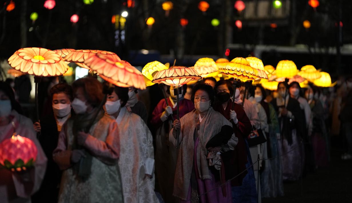Umat Buddha Korea Selatan mengenakan masker membawa lentera lotus berwarna-warni selama upacara pencahayaan untuk merayakan ulang tahun Buddha yang akan datang pada 8 Mei, di Seoul, Korea Selatan (5/4/2022). (AP Photo/Lee Jin-man)