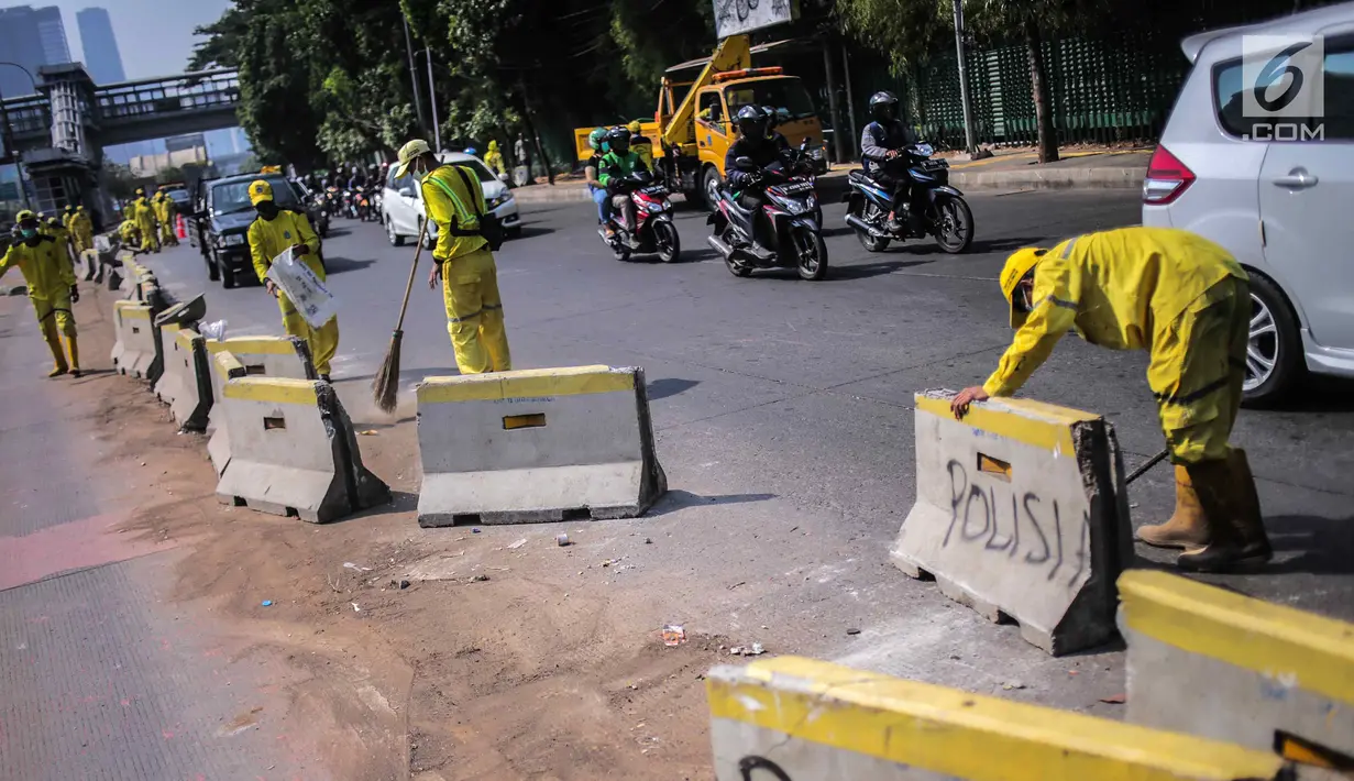 Petugas Dinas Bina Marga DKI Jakarta memperbaiki separator busway di kawasan Jalan Gatot Subroto, Jakarta, Selasa (1/10/2019). Separator busway dirusak massa saat terjadi bentrok antara polisi dengan demonstran di kawasan tersebut. (Liputan6.com/Faizal Fanani)