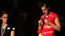 Carolina Marin memperhatikan medali emas yang diraihnya, sementara Saina Nehwal meliriknya. Minggu (16/8/2015). (Bola.com/Arief Bagus)