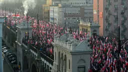 Orang-orang mengibarkan bendera nasional Polandia saat pawai untuk menandai Hari Kemerdekaan Nasional Polandia di Warsawa, Polandia, 11 November 2021. Hari Kemerdekaan Nasional Polandia dirayakan pada 11 November untuk memperingati ulang tahun Republik Polandia Kedua. (Adam Chelstowski/AFP)
