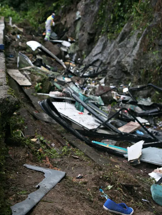 Petugas penyelamat berjalan diantara puing-puing bus yang terjun bebas ke jurang di negara bagian Sao Paulo, Brasil, Kamis (9/6). Kecelakaan terjadi pada Rabu, 8 Juni 2016, sekitar pukul 23:40 di pinggiran Mogi das Cruzes. (Jonny UEDA/AFP)