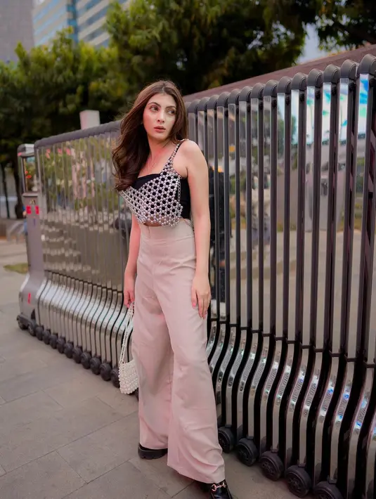 Sarah Keihl mengenakan atasan tank top hitam dengan aksesori di bagian depannya, dipadu high-waisted pants berwarna cokelat muda. [Foto: Instagram/sarahkeihl]