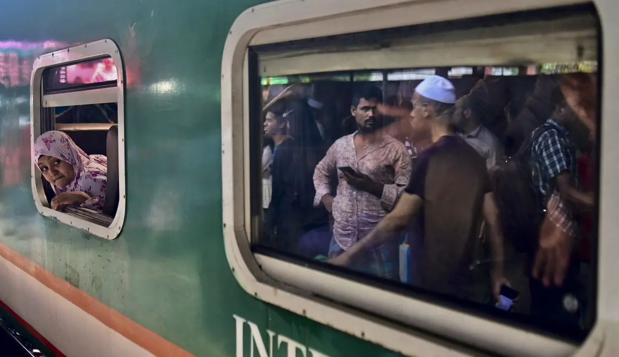 Seorang perempuan melihat keluar dari kereta api di stasiun kereta Bandara Dhaka ketika orang-orang melakukan perjalanan ke kampung halaman mereka menjelang festival Muslim Idul Adha atau 'Festival Kurban', di Dhaka, Bangladesh pada 28 Juni 2023. (Munir uz Zaman / AFP)