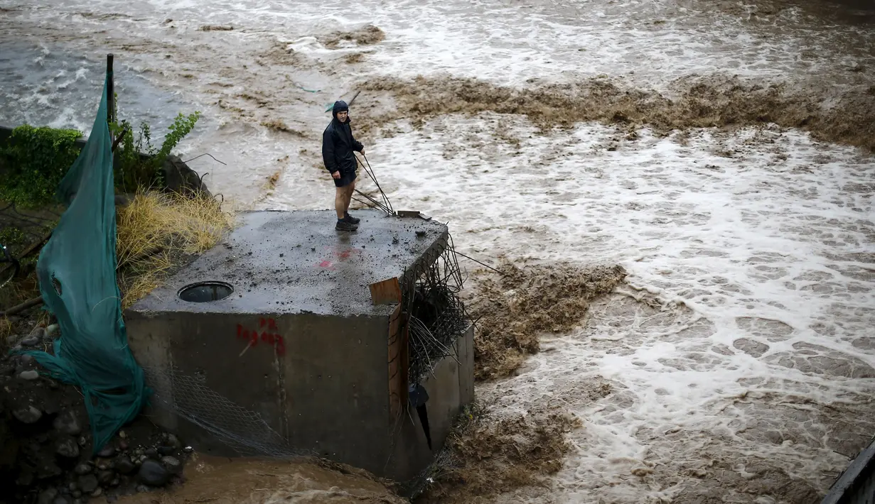 Seorang pria terlihat di sebelah sungai saat banjir melanda Ibu Kota Chile, Santiago, Minggu (17/4). Hujan lebat dan parah di Ibu Kota Chile selama akhir pekan lalu menyebabkan 1 orang tewas dan 7 orang masih dinyatakan hilang. (REUTERS/Ivan Alvarado)