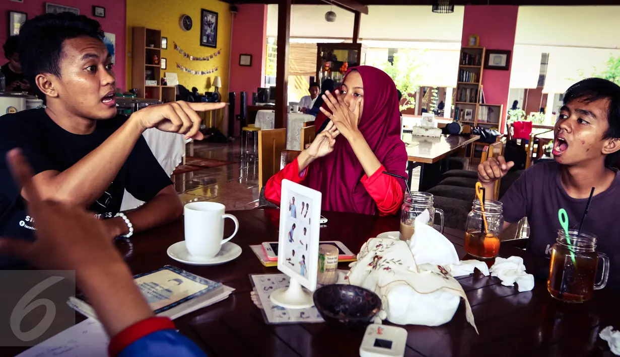 Sejumlah pengunjung berbincang menggunakan bahasa isyarat saat mengunjungi kafe Finger Talk di Pamulang, Tangsel, Sabtu (20/2). Ada yang unik dari kafe ini, dimana para pramusajinya merupakan penyandang tunarungu. (Liputan6.com/Fery Pradolo)