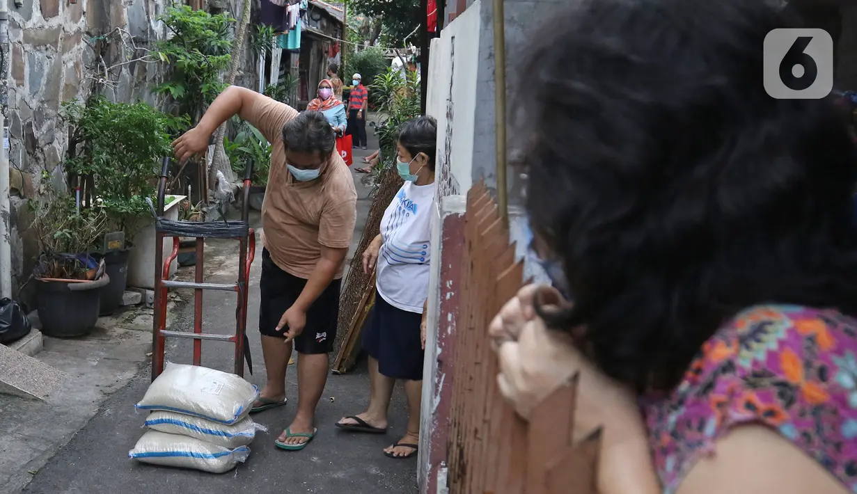 Pengurus RT menyalurkan bantuan sosial non tunai berupa beras di kawasan RW 03 Kelurahan Tanah Tinggi, Jakarta, Kamis (29/7/2021). Beras bantuan itu didistribusikan kepada 1.007.379 Keluarga Penerima Manfaat (KPM) di lima wilayah Kota Administrasi dan Kepulauan Seribu. (Liputan6.com/Herman Zakharia)