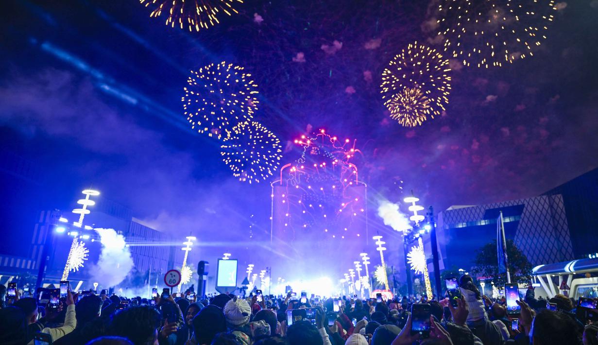 Orang-orang menyaksikan kembang api menerangi langit selama perayaan Tahun Baru di Lusail, Qatar, pada 1 Januari 2026. (Mahmud HAMS/AFP)