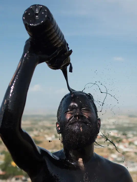 Peserta melumuri tubuhnya dengan oli saat mengikuti Festival Cascamorras di Baza, Granada, Spanyol, Kamis (6/9). Festival ini menggambarkan pertempuran Kota Baza dan Guadix memperebutkan patung perawan suci, Pieta. (JORGE GUERRERO/AFP)