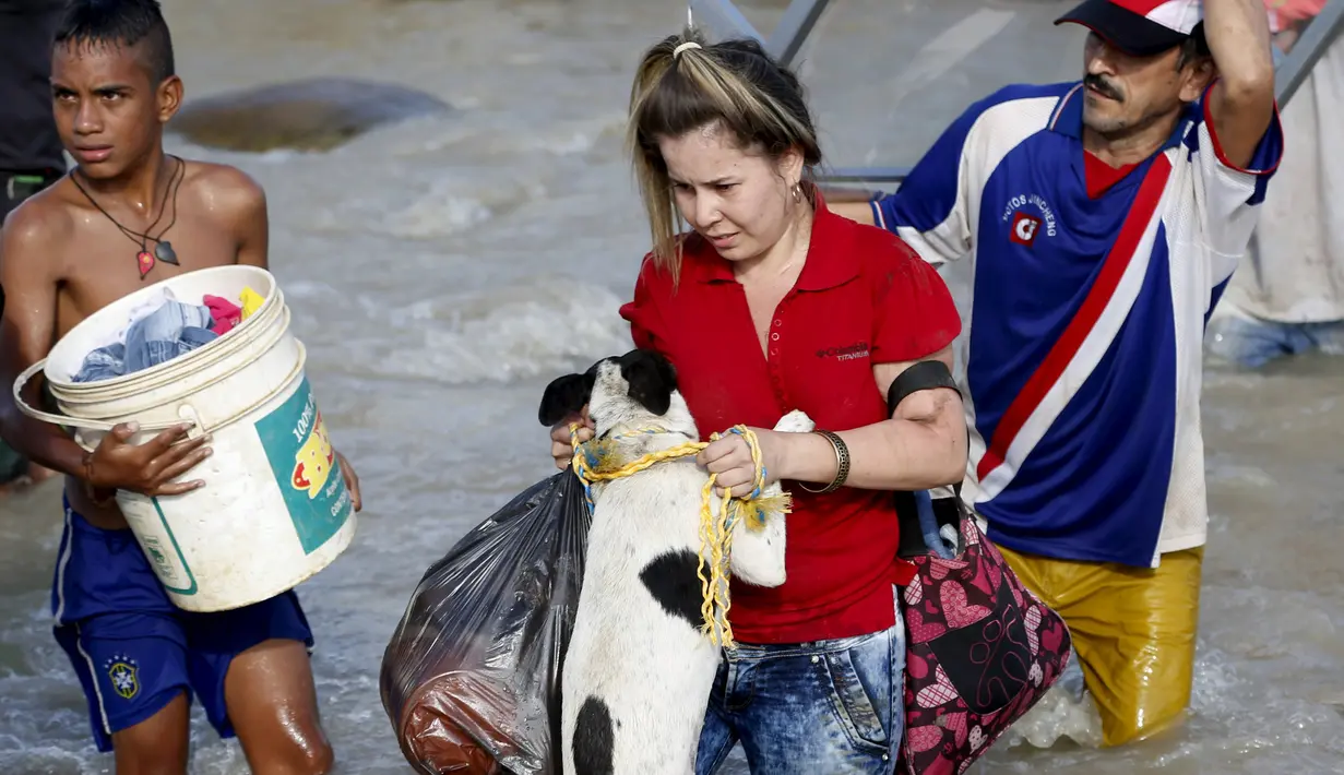Seorang wanita membawa anjing saat dia melintasi perbatasan sungai Tachira dengan Venezuela ke Kolombia, (25/8/2015). Pemerintah Venezuela menutup perbatasan dengan Kolombia dan mendeportasi ratusan warga Kolombia. (REUTERS/Jose Miguel Gomez)