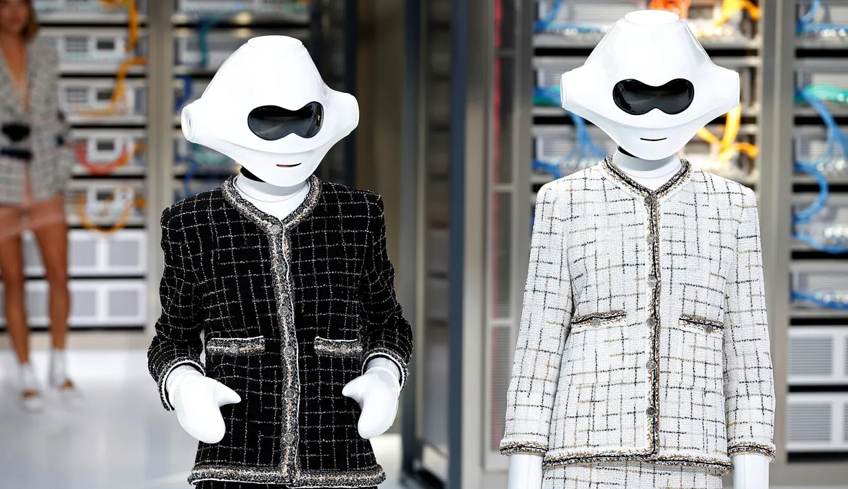 Dua robot berwarna putih berpose mengenakan rancangan desainer Karl Lagerfeld untuk koleksi musim semi 2017 di Paris Fashion Week, Prancis, Selasa (4/10). Kedua robot memakai setelan klasik Chanel dengan warna hitam dan putih. (REUTERS/Charles Platiau)