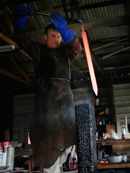 John Lundemo bersiap medinginkan pedang buatannya di bengkelnya di New Hampton, New York, (2/3). Lundemo membuat pedang terinspirasi oleh sejarah dari unsur barat dan timur. (AP Photo/Seth Wenig)
