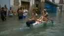 Warga mengapung di atas styrofoam untuk melewati jalanan yang terendam banjir di Hanava, Kuba, Minggu (10/9). Badai irma yang melanda pantai timur Perairan Kuba pada Jumat waktu setempat menyebabkan sebagian kota terendam banjir. (AP/Ramon Espinosa)