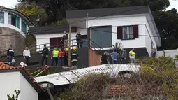Orang-orang melihat kondisi sebuah bus pariwisata berisi rombongan turis dari Jerman yang terguling di Kota Canico, Pulau Madeira, Portugal, Rabu (17/4). Warga setempat melaporkan bahwa cuaca baik-baik saja pada saat kecelakaan, yang terjadi di sore hari. (RUI SILVA / AFP)
