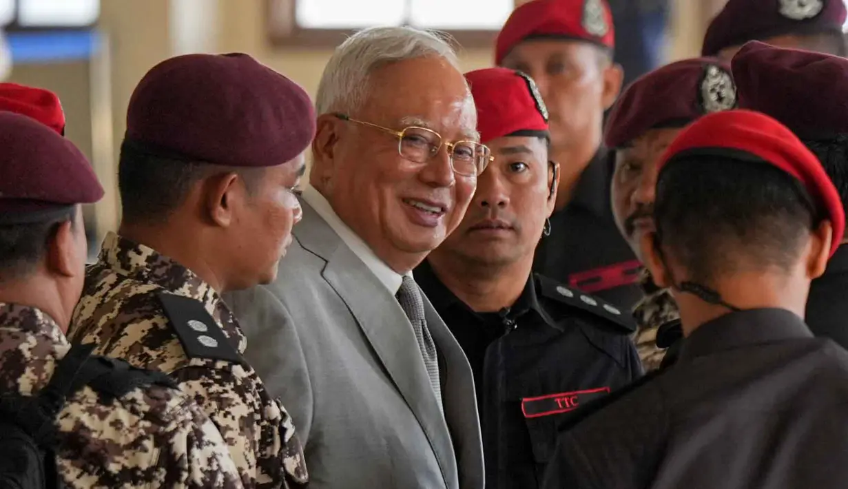 Saat ini, mantan Perdana Menteri Malaysia, Najib Razak, yang kini berusia 72 tahun, masih menjalani masa hukumannya di Penjara Kajang sejak 23 Agustus 2022 setelah dinyatakan bersalah karena menggelapkan dana sebesar RM42 juta milik SRC International Sdn Bhd. Tampak dalam foto, mantan Perdana Menteri Malaysia, Najib Razak (tengah) dikawal oleh petugas penjara saat tiba di Kompleks Pengadilan Tinggi Kuala Lumpur, Malaysia, Senin 22 Desember 2025. (AP Photo/Azneal Ishak)