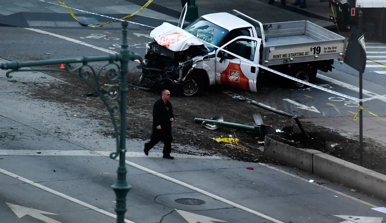 Petugas investigasi berjalan dekat sebuah truk yang menabrak pejalan kaki dan pesepeda di Lower Manhattan, New York, Selasa (31/10). Usai menabrak, tersangka meninggalkan kendaraan tersebut dan menampilkan senjata api yang diduga imitasi. (Don EMMERT/AFP)