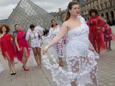 Seorang model ukuran plus berpose di depan piramida Louvre di Paris, Prancis (4/1). Mereka tampil di ruang publik dengan menggunakan busana layaknya di sebuah acara fashion show. (AFP/Thomas Samson)