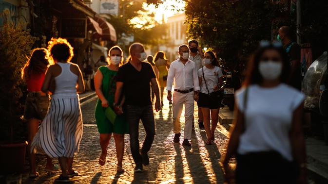 Turis yang mengenakan masker untuk melindungi dari penyebaran virus corona berjalan di kota Ayvalik di Laut Aegea, Turki, Rabu (9/9/2020). Turki telah mewajibkan penggunaan masker di semua lokasi selain di rumah, menyusul lonjakan jumlah infeksi COVID-19. (AP Photo/Emrah Gurel)