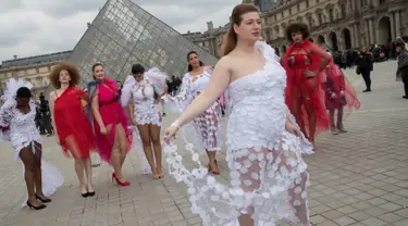 Seorang model ukuran plus berpose di depan piramida Louvre di Paris, Prancis (4/1). Mereka tampil di ruang publik dengan menggunakan busana layaknya di sebuah acara fashion show. (AFP/Thomas Samson)