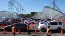 Relawan berjalan saat orang-orang yang telah menerima vaksin berada di dalam kendaraan mereka di pusat vaksinasi COVID-19 drive-thru massal di tempat parkir Six Flags Magic Mountain di Valencia, California, Selasa (2/2/2021). Mario Tama/Getty Images/AFP)