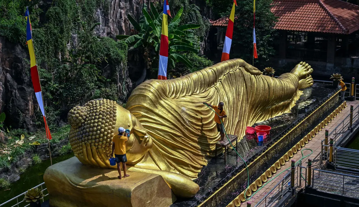 Prosesi memandikan dilakukan dengan menyiram semua bagian patung Buddha tidur dengan air yang berisi bunga. Selanjutnya, permukaan patung dibersihkan menggunakan sikat. (JUNI KRISWANTO/AFP)