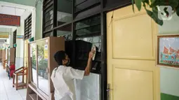 Petugas mengelap kaca di SD Negeri Kota Bambu 03/04, Jakarta, Sabtu (21/11/2020). Pemerintah pusat memberikan kewenangan pemerintah daerah membuka sekolah dan melakukan pembelajaran tatap muka pada semester genap tahun ajaran 2020/2021. (Liputan6.com/Faizal Fanani)