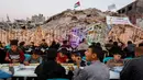 Warga Palestina berkumpul untuk berbuka puasa bersama yang diselenggarakan oleh Yayasan IHH Turki, di tengah reruntuhan bangunan yang hancur di Kota Gaza pada Rabu 18 Februari 2026. Puluhan hingga ratusan warga Palestina di Gaza duduk bersama untuk berbuka puasa bersama di antara puing-puing bangunan yang hancur. (Omar AL-QATTAA/AFP)