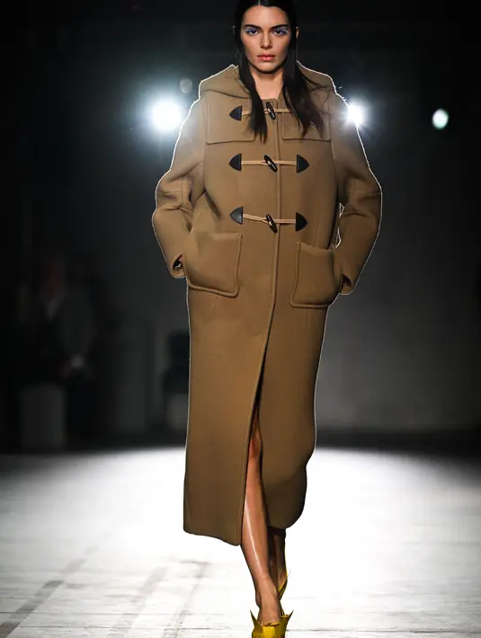 Kendall Jenner berjalan di catwalk saatmempersembahkan kreasi Prada selama Koleksi Wanita Musim Gugur-Musim Dingin 2023-2024 sebagai bagian dari Fashion Week di Milan pada 23 Februari 2023. Kendaall menambahkan beberapa inci ekstra tinggi ke bingkai patungnya dengan sepasang tumit gaya origami kuning keemasan yang unik, dihiasi dengan bunga. (AFP/Marco Bertorello)