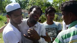 Alif Jukhar (kedua kiri) menangis setelah menguburkan kedua orang tuanya di pemakaman di Sha Porir Dwip, Teknaf (9/10). Alif Jukhar, yang telah lama tinggal di Bangladesh, kehilangan sembilan saudara termasuk ibu dan ayahnya. (AFP Photo/Munir Uz Zaman)