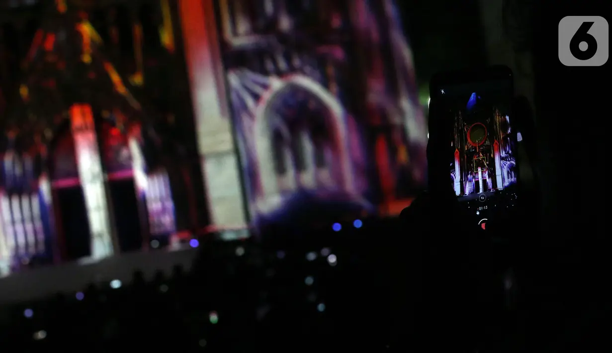 Umat kristiani merekam pemutaran video mapping di Gereja Katedral yang bercerita sejarah Kongres Pemuda II , Jakarta, Minggu (27/12/2019). Pemutaran video mapping ini untuk memperingati Hari Sumpah Pemuda ke-91 dan berlangsung hingga 28 Oktober. (Liputan6.com/Helmi Fithriansyah)