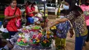 Seorang wanita dan anak-anak membeli lentera mengambang untuk dilepaskan ke sungai selama festival Loy Krathong di provinsi Narathiwat, Thailand selatan (8/11/2022). (AFP/Madaree Tohlala)