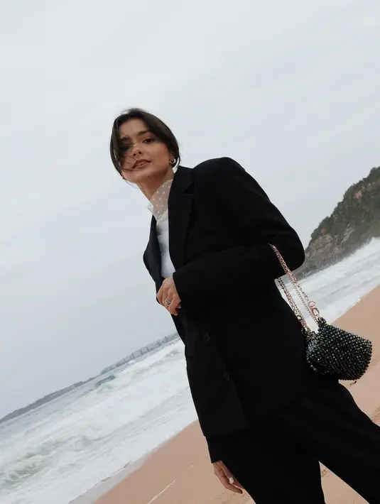 Kembali ke alam, kali ini Amanda Rawles tampak memilih pantai sebagai latar fotonya. Ia mengenakan dalam dalam putih dengan detail turtleneck, dilapisinya dengan coat hitam, dan menenteng mini bag hitam berantai emas, sungguh tampilan yang menarik untuk dijadikan inspirasi. Foto: Instagram.
